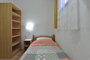 a small bedroom with a bed with a quilt on it at Apartmani Marko in Gdinj