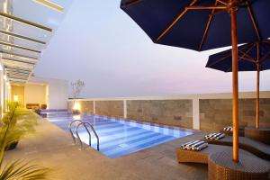 a swimming pool with an umbrella in a building at Swiss-Belinn Airport Surabaya in Sidoarjo