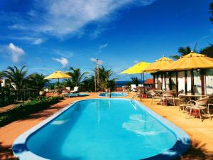 a swimming pool with tables and umbrellas on a resort at Pousada Cultural Canto dos Poetas in Aquiraz