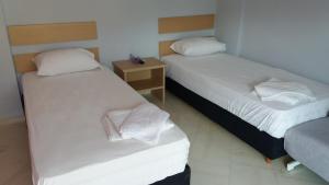 イラクリトサにあるToula Apartmentsの白いシーツとナイトスタンドが備わる客室のベッド2台