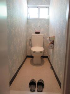 a bathroom with a toilet with a window and a pair of shoes at Nikko Pension L'escale in Nikko