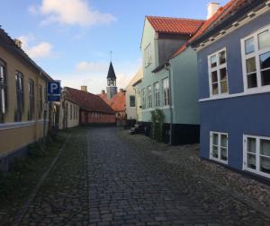 a cobblestone street in a town with a church at Baghuset in Ebeltoft