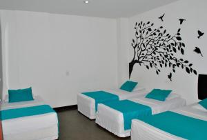 a room with three beds with a tree on the wall at Hotel Los Cristales in Santa Rosa de Cabal