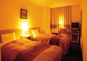 a hotel room with two beds and a television at Hirosaki Plaza Hotel in Hirosaki