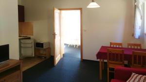 a living room with a table and a kitchen with a window at Apartmány Maruška in Stachy