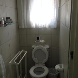 a small bathroom with a toilet with the seat up at Broadway in Durban +10 photos