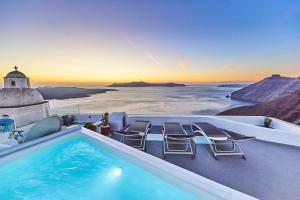 a pool with chairs and a view of the ocean at Trieris Villa & Suites in Fira