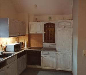 a small kitchen with white cabinets and a microwave at Ferienwohnung Bender in Gemünden