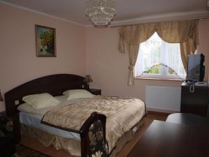 a bedroom with a bed and a television and a window at Apartamenty Willa Park in Żagań