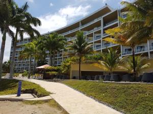 un bâtiment sur la plage avec des palmiers et un trottoir dans l'établissement Makana Suite 6-11, à Tonsupa