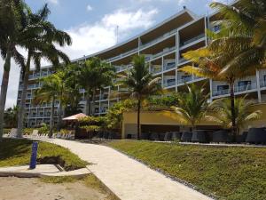 a building on the beach with palm trees and a sidewalk at Makana Suite 6-11 in Tonsupa