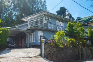 a blue house with a balcony on top of it at Mount Mary Inn in Nuwara Eliya