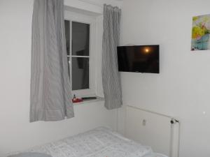 a bedroom with a bed and a television on the wall at Ferienwohnung Ortlieb Laboe in Laboe