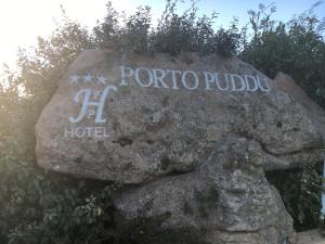 a sign on a rock with the name of a hotel at Hotel Porto Puddu - Il Nido dei Gabbiani in Porto Pollo
