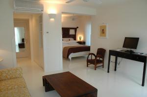 a living room with a bed and a desk with a television at Il San Francesco Charming Hotel in Sabaudia