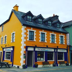 un gran edificio naranja con bancos delante en Lynch's on the Pier, en Castletownbere