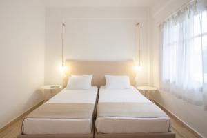 two beds in a room with white walls and a window at Paris Studios & Apartment in Agia Paraskevi