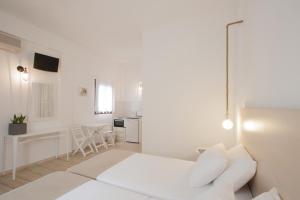 a white bedroom with a bed and a kitchen at Paris Studios & Apartment in Agia Paraskevi