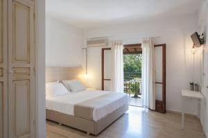 a white bedroom with a bed and a window at Paris Studios & Apartment in Agia Paraskevi