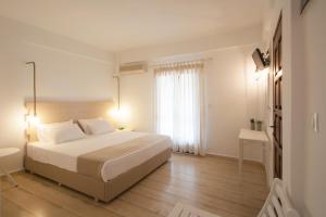 a white bedroom with a bed and a window at Paris Studios & Apartment in Agia Paraskevi