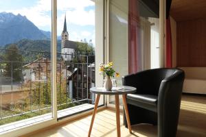 einen Stuhl und einen Tisch vor einem großen Fenster in der Unterkunft Hotel Restaurant GABRIEL in Scuol