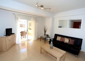 ein Wohnzimmer mit einem schwarzen Sofa und einem Tisch in der Unterkunft Penelope Court Apartment 102 in Larnaka