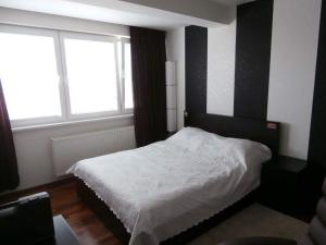 a bedroom with a white bed and two windows at Apartmán Deluxe in Banská Bystrica