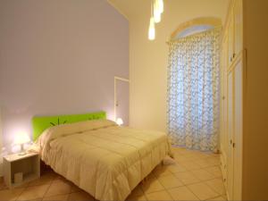 een slaapkamer met een bed met een groen hoofdeinde en een raam bij B&B Corte dell' Idume in Lecce