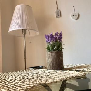 Una mesa con una lámpara y un jarrón de flores moradas. en Studio Confort, en Bucarest