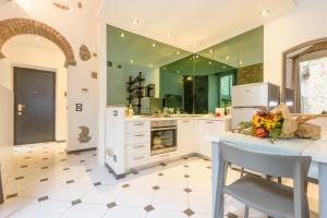 uma cozinha com paredes verdes, armários brancos e uma mesa em Terrazza Rivola em Bérgamo