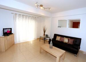 ein Wohnzimmer mit einem schwarzen Sofa und einem Tisch in der Unterkunft Penelope Court Apartment 102 in Larnaka