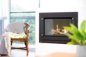 a chair and a fireplace in a living room at Sea View at Silver Sands - C21 SouthCoast Holidays in Aldinga Beach