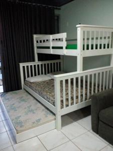 two white bunk beds in a room with a couch at Ajuricaba Suítes 8 in Manaus