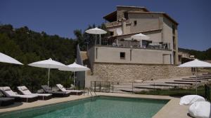 a building with a swimming pool with chairs and umbrellas at Hotel Mas de la Serra in Fuentespalda