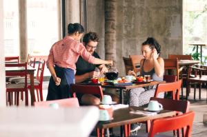 a group of people standing around a table in a restaurant at Grandmas Plus Hotel Seminyak in Seminyak