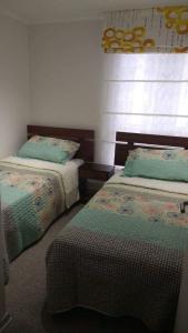 a bedroom with two beds with green and white sheets at Departamento arica in Arica