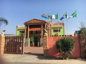 a fence in front of a building with flags at Tassili Lodge in Kempton Park