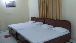 a bedroom with two beds with white sheets at Champions Bungalow in Rāmnagar