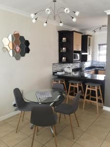 Una cocina y un comedor con una mesa de cristal y sillas. en Aya Luxury Apartments 56, en Durban