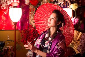 une femme porte un parapluie rouge dans l'établissement Kinosaki Onsen Hanakouji Saigetsu, à Toyooka