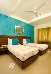 two beds in a bedroom with blue walls at BIZZ Tamanna Hotel in Pune
