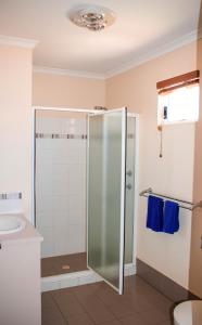a bathroom with a shower and a sink at Outback Oasis Caravan Park in Carnarvon