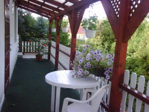 a wooden pergola with a white table and flowers at Relax Apartmanok in Zalakaros