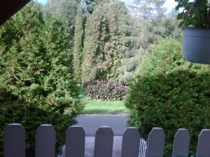 a fence in front of a yard with trees at Relax Apartmanok in Zalakaros