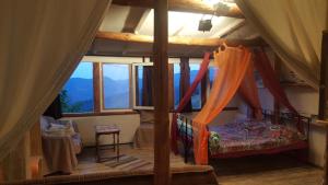 a bedroom with a canopy bed in a room with windows at Zornica Guest House in Chepelare