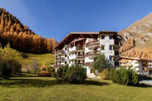 ザムナウンにあるHotel Garni Chasa Novaの山中のホテルで、木々や芝生が茂っています。