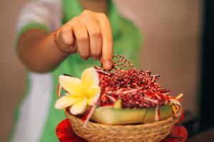 a person is pointing at a basket of food at Grandmas Plus Hotel Seminyak in Seminyak