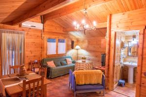 Sala de estar de una cabaña de madera con sofá y mesa en La Casa del Chaparro, en Arcos de la Frontera