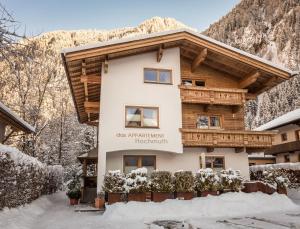 a house in the snow in front of a mountain at Alpen Appartements Hochmuth in Mayrhofen