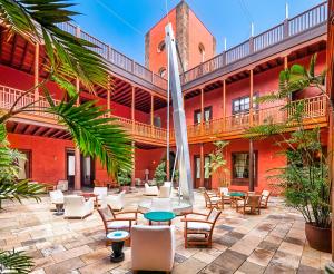 a courtyard of a red building with chairs and tables at Hotel San Roque in Garachico